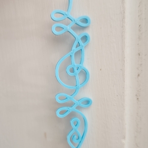 a unalome with a treble clef incorporated. it's in blue plastic.